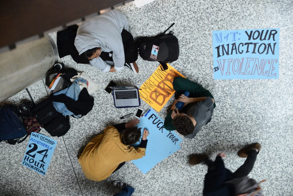 Following a student death on Sept. 30, 2019, students create signs calling out the university for its lack of supports.